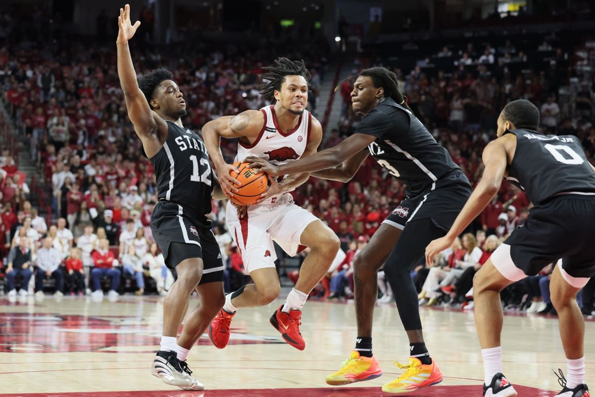 Mar 8, 2025; Fayetteville, Arkansas, USA; Arkansas Razorbacks guard D.J. Wagner (21) drives between Mississippi State Bulldogs guard Josh Hubbard (12) and forward KeShawn Murphy (3) during the first half at Bud Walton Arena. Mandatory Credit: Nelson Chenault-Imagn Images