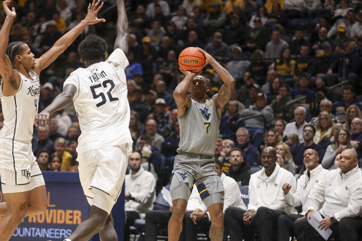 Mar 8, 2025; Morgantown, West Virginia, USA; West Virginia Mountaineers guard Javon Small (7) shoots a three pointer among several UCF Knights defenders during the first half at WVU Coliseum. Mandatory Credit: Ben Queen-Imagn Images