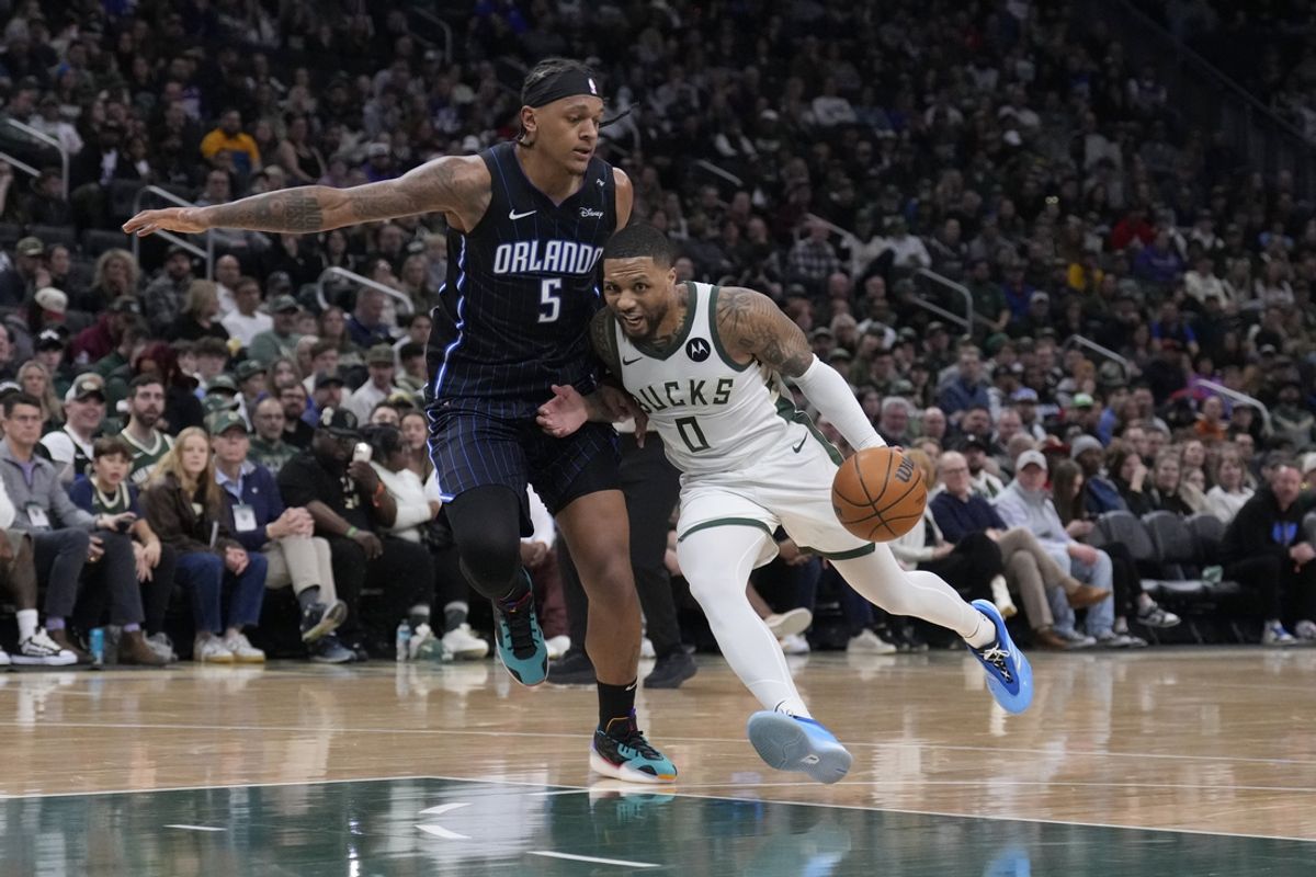 Mar 8, 2025; Milwaukee, Wisconsin, USA; Milwaukee Bucks guard Damian Lillard (0) drives to the basket against Orlando Magic forward Paolo Banchero (5) in the first half at Fiserv Forum. Mandatory Credit: Michael McLoone-Imagn Images