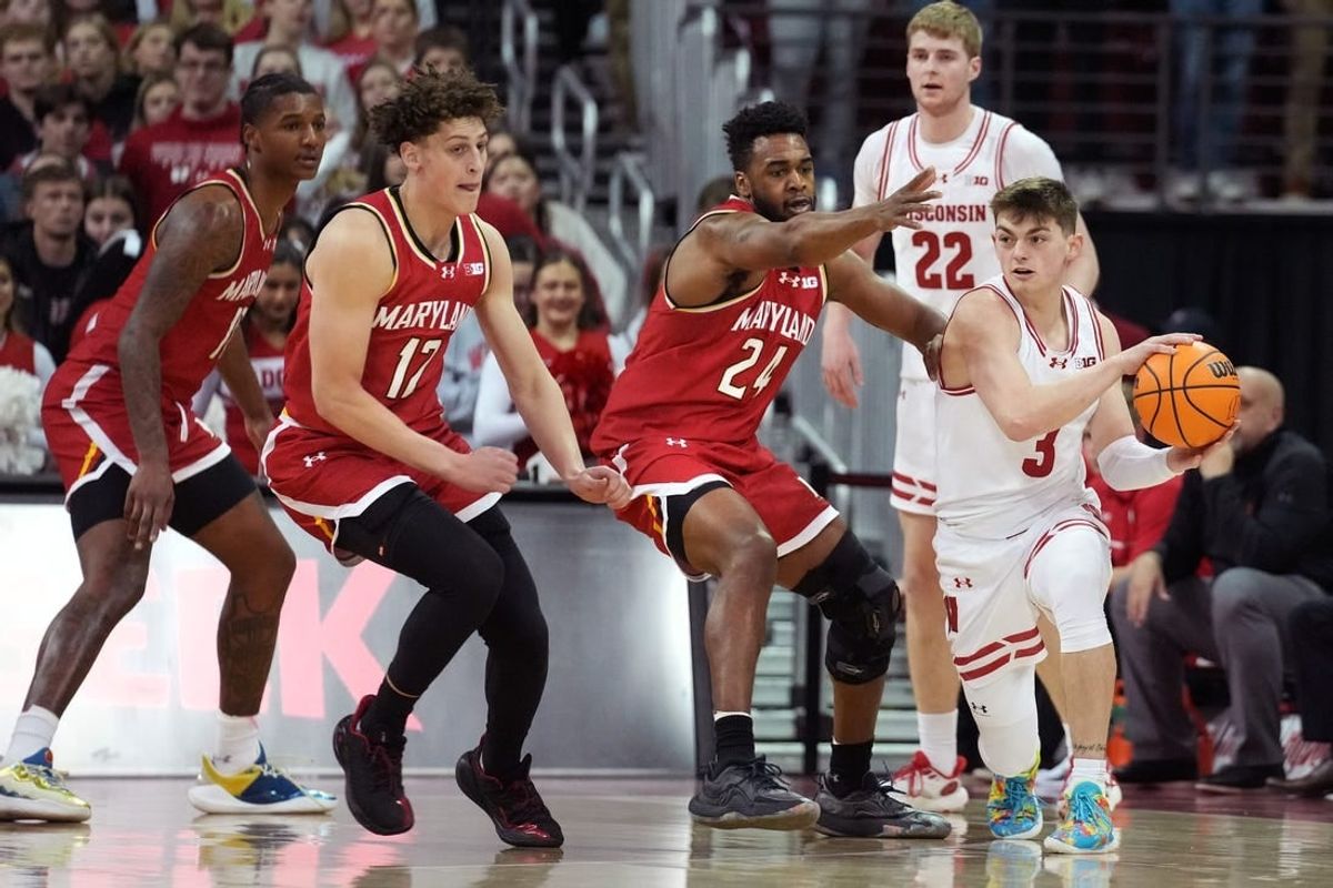 Feb 20, 2024; Madison, Wisconsin, USA;  Wisconsin Badgers guard Connor Essegian (3) passes the ball against Maryland Terrapins forward Donta Scott (24) and Maryland Terrapins forward Jamie Kaiser Jr. (12) during the first half at the Kohl Center.