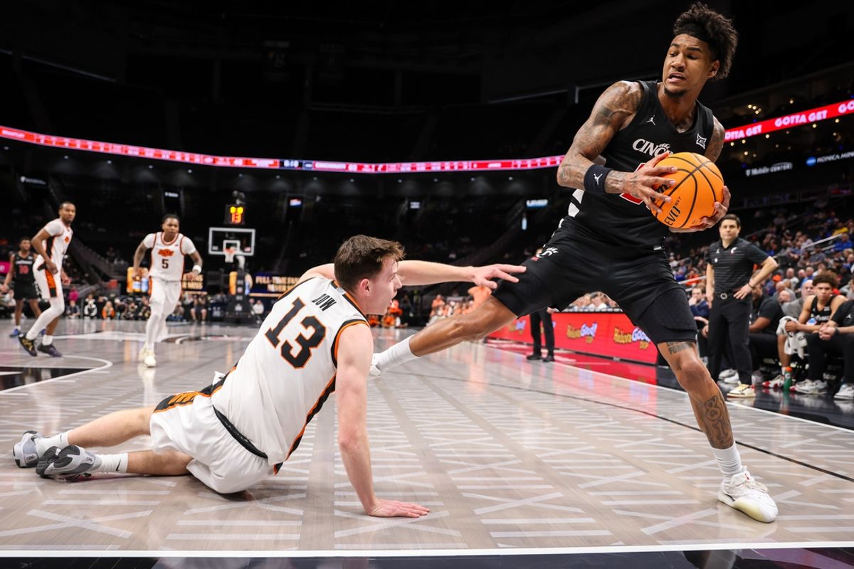 Mar 11, 2025; Kansas City, MO, USA; Cincinnati Bearcats forward Dillon Mitchell (23) saves a ball from going out of bounds around Oklahoma State Cowboys guard Connor Dow (13) during the second half at T-Mobile Center. Mandatory Credit: William Purnell-Imagn Images