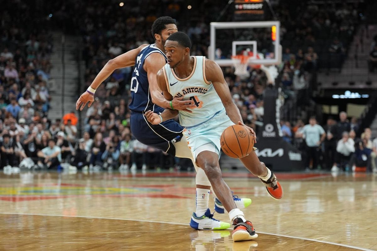 Mar 12, 2025; San Antonio, Texas, USA; San Antonio Spurs guard De'Aaron Fox (4) dribbles past Dallas Mavericks guard Spencer Dinwiddie (26) in the first half at Frost Bank Center. Mandatory Credit: Daniel Dunn-Imagn Images