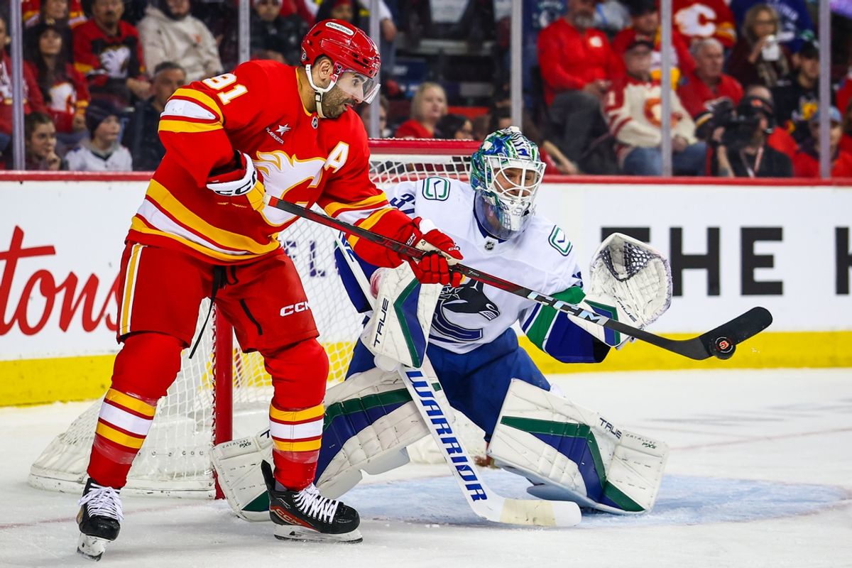 Mar 12, 2025; Calgary, Alberta, CAN; Calgary Flames center Nazem Kadri (91) redirects the puck against Vancouver Canucks goaltender Kevin Lankinen (32) during the second period at Scotiabank Saddledome. Mandatory Credit: Sergei Belski-Imagn Images