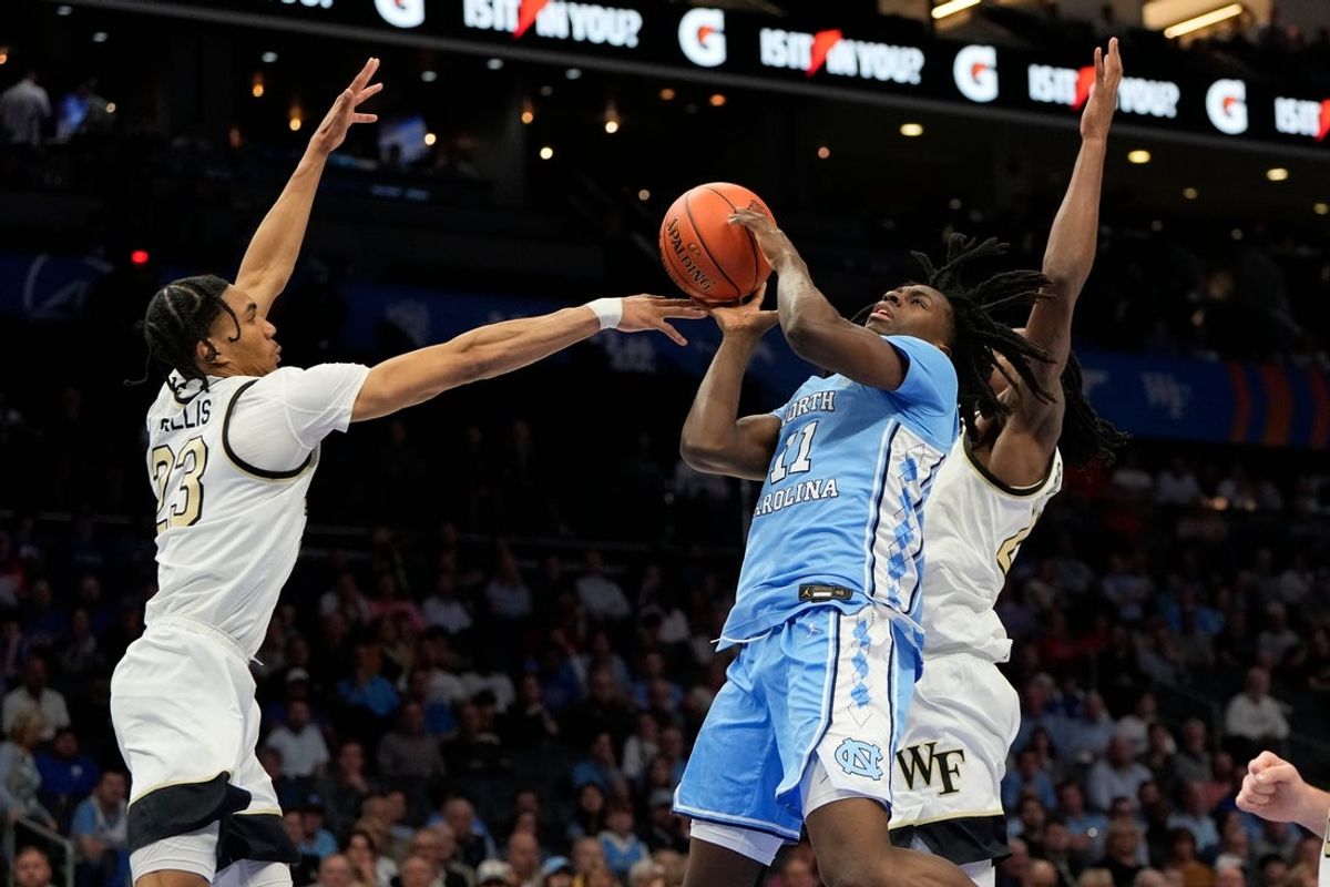 Mar 13, 2025; Charlotte, NC, USA; North Carolina Tar Heels guard Ian Jackson (11) shoots as Wake Forest Demon Deacons guard Hunter Sallis (23) and forward Tre'Von Spillers (25) defend in the second half at Spectrum Center. Mandatory Credit: Bob Donnan-Imagn Images