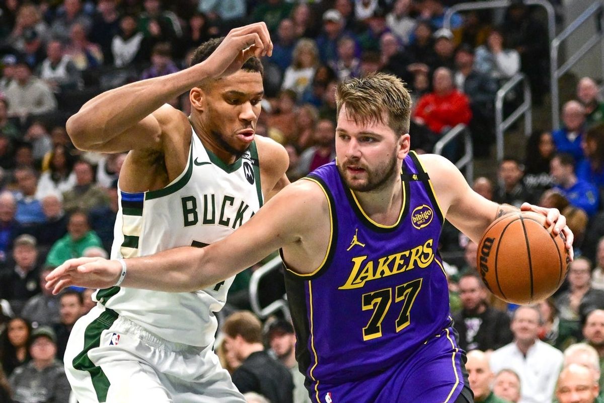 Mar 13, 2025; Milwaukee, Wisconsin, USA;  Los Angeles Lakers guard Luka Doncic (77) drives to the basket against Milwaukee Bucks forward Giannis Antetokounmpo (34) in the third quarter at Fiserv Forum. Mandatory Credit: Benny Sieu-Imagn Images