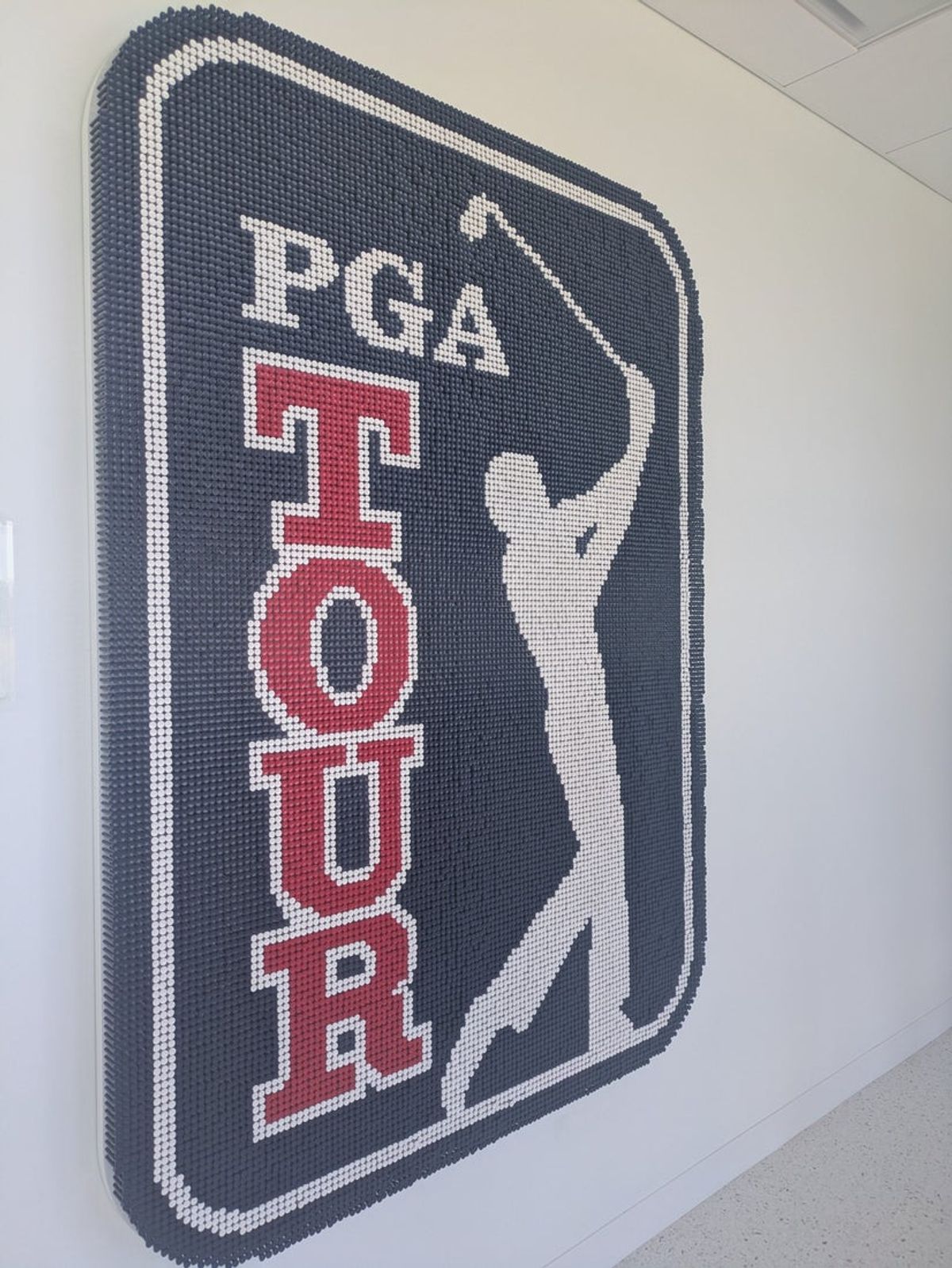 A giant PGA Tour logo made of an estimated 21,000 tees is on the wall inside the PGA Tour Studios building in Ponte Vedra Beach, Florida, on March 14, 2025. [Clayton Freeman/Florida Times-Union]