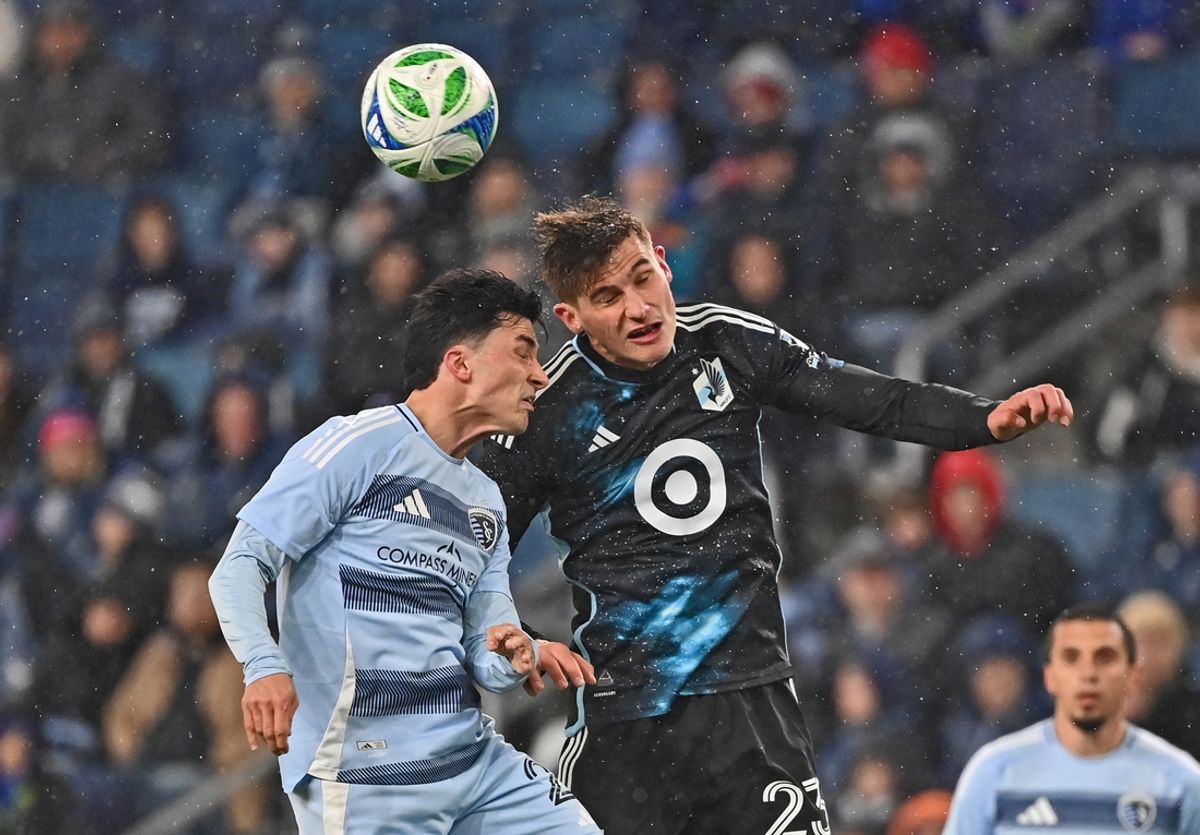 Mar 15, 2025; Kansas City, Kansas, USA;  Minnesota United defender Morris Duggan (23) heads the ball against Sporting Kansas City defender Zorhan Bassong (22) in the first half at Children's Mercy Park. Mandatory Credit: Peter Aiken-Imagn Images