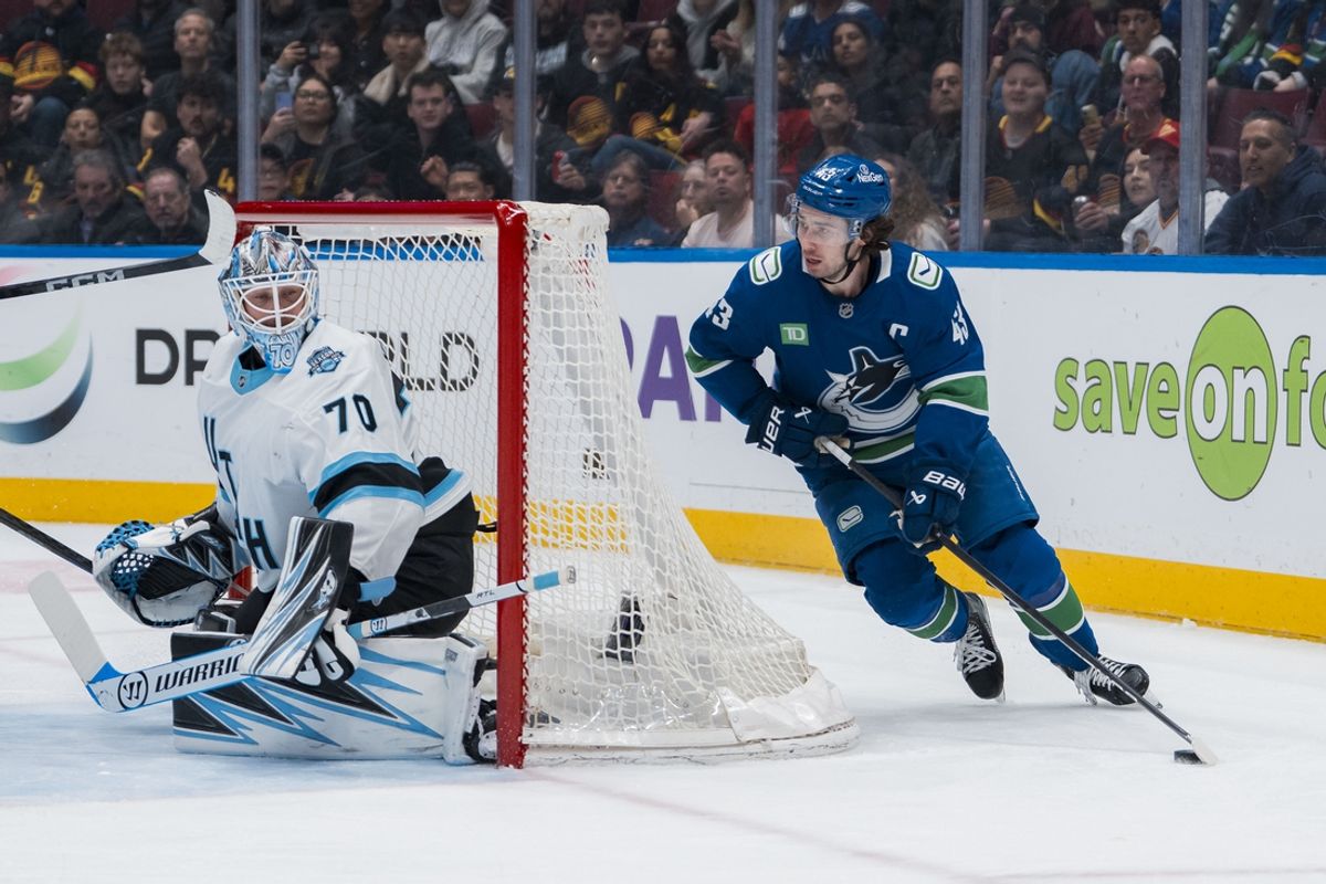 Mar 16, 2025; Vancouver, British Columbia, CAN; Utah Hockey Club goalie Karel Vejmelka (70) watches Vancouver Canucks defenseman Quinn Hughes (43) handle the puck in the first period at Rogers Arena. Mandatory Credit: Bob Frid-Imagn Images