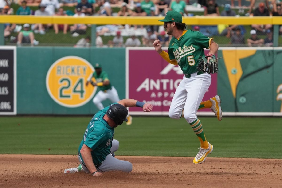 Mar 17, 2025; Mesa, Arizona, USA; Oakland Athletics shortstop Jacob Wilson (5) avoids Seattle Mariners outfielder Luke Raley (20) in the second inning at Hohokam Stadium. Mandatory Credit: Rick Scuteri-Imagn Images