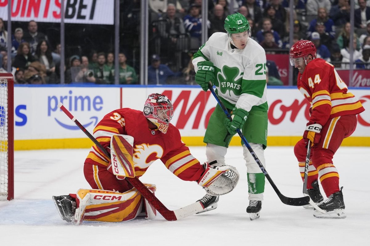 Mar 17, 2025; Toronto, Ontario, CAN; Calgary Flames goaltender Dustin Wolf (32) makes a save as Toronto Maple Leafs forward Pontus Holmberg (29) tries to deflect the puck during the first period at Scotiabank Arena. Mandatory Credit: John E. Sokolowski-Imagn Images
