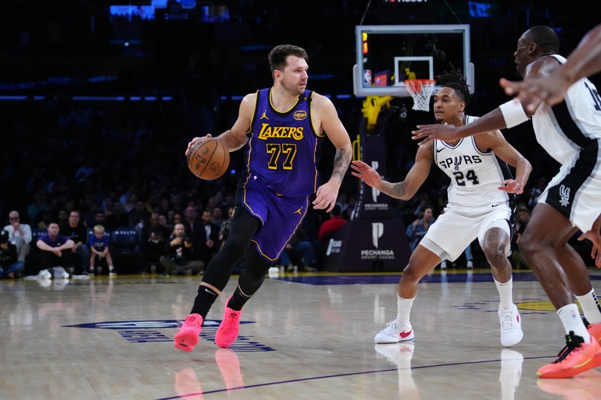 Mar 17, 2025; Los Angeles, California, USA; Los Angeles Lakers guard Luka Doncic (77) dribbles the ball against San Antonio Spurs guard Devin Vassell (24) in the first half at Crypto.com Arena. Mandatory Credit: Kirby Lee-Imagn Images