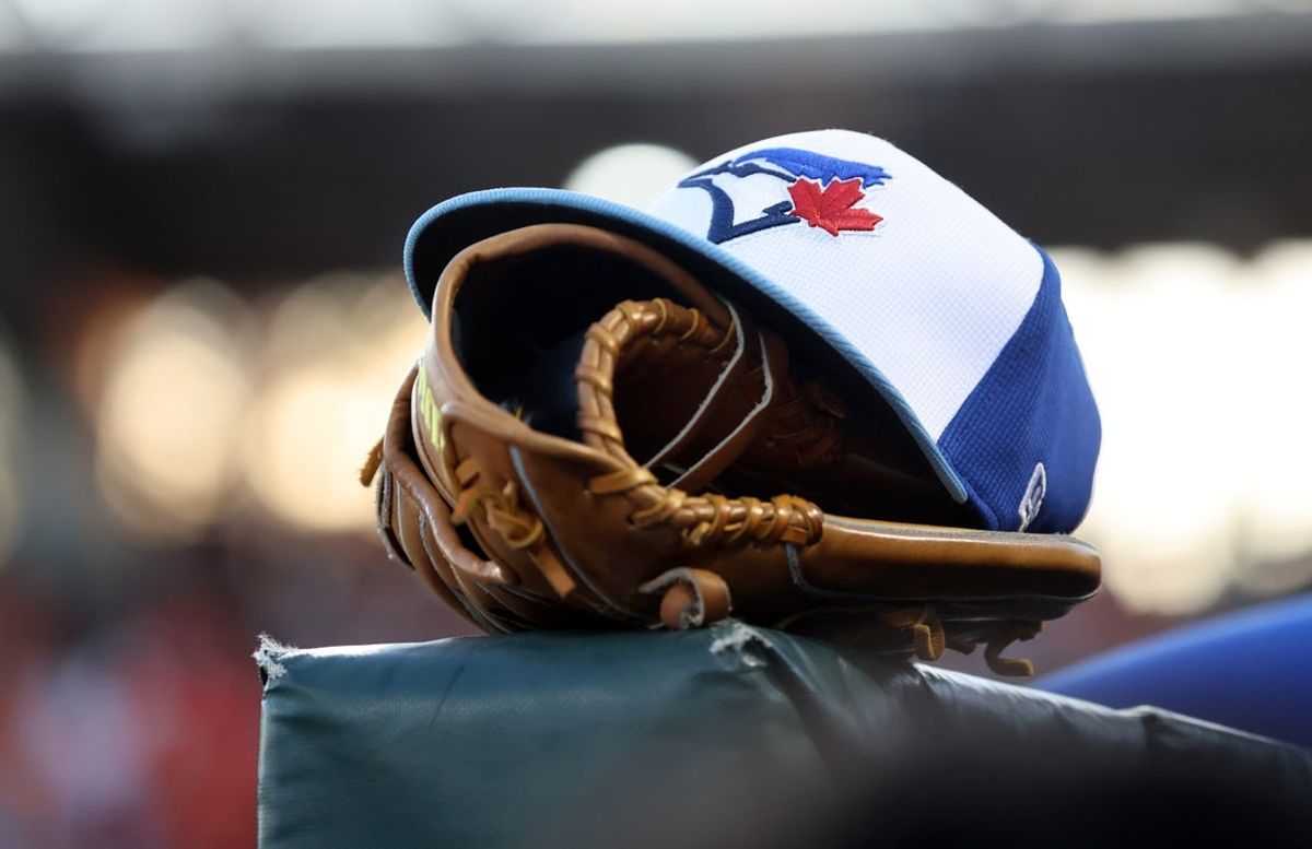 Mar 18, 2025; Sarasota, Florida, USA;  A detail view of a Toronto Blue Jays hat and glove against the Baltimore Orioles at Ed Smith Stadium. Mandatory Credit: Kim Klement Neitzel-Imagn Images