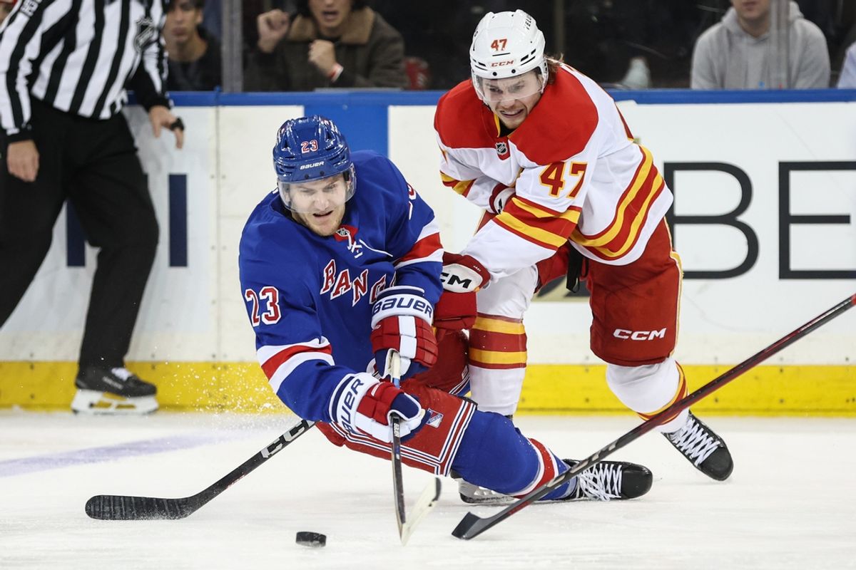 Mar 18, 2025; New York, New York, USA;  New York Rangers defenseman Adam Fox (23) and Calgary Flames center Connor Zary (47) battle for control of the puck in the third period at Madison Square Garden. Mandatory Credit: Wendell Cruz-Imagn Images