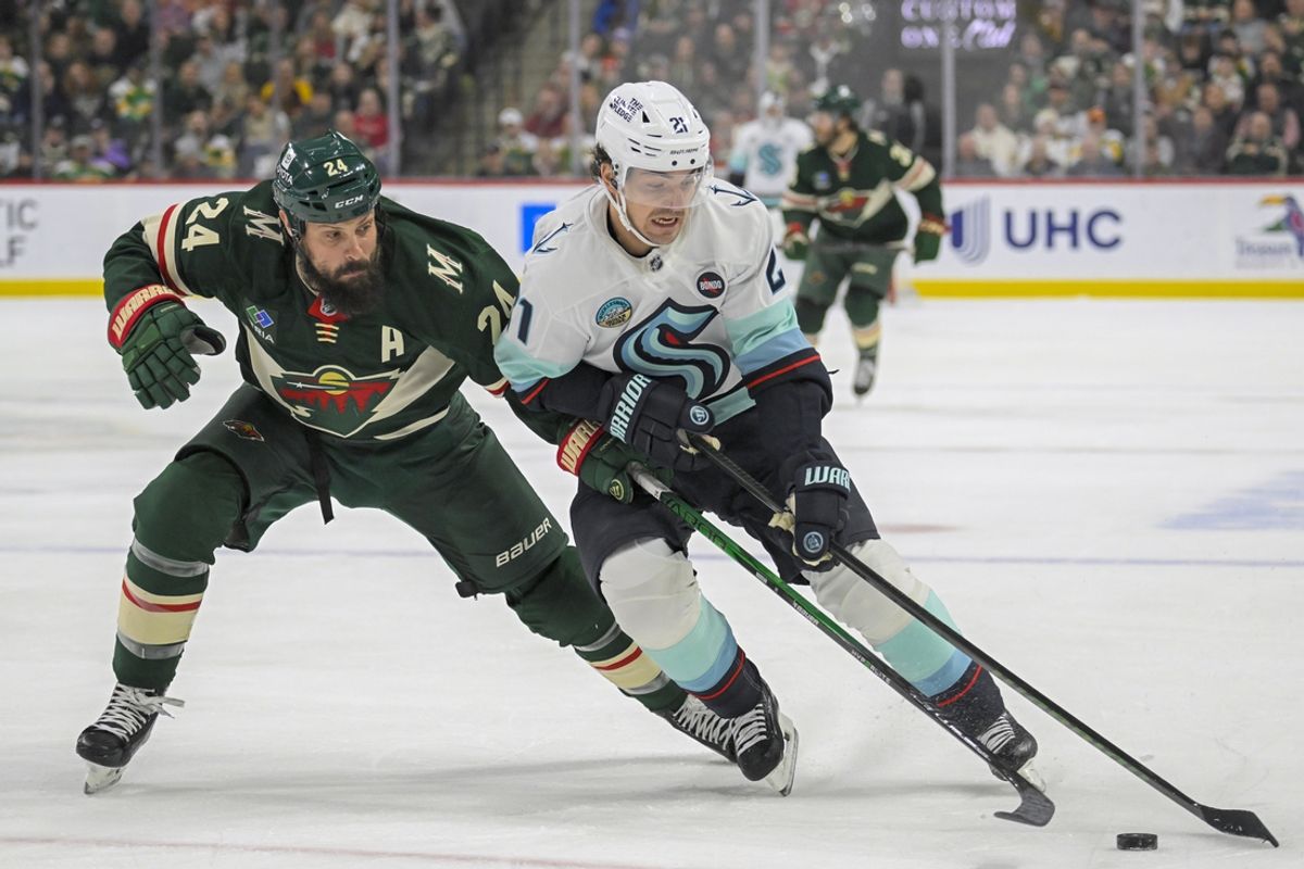 Mar 19, 2025; Saint Paul, Minnesota, USA;  Seattle Kraken forward Mikey Eyssimont (21) protects the puck from Minnesota Wild defenseman Zach Bogosian (24) during the first period at Xcel Energy Center. Mandatory Credit: Nick Wosika-Imagn Images