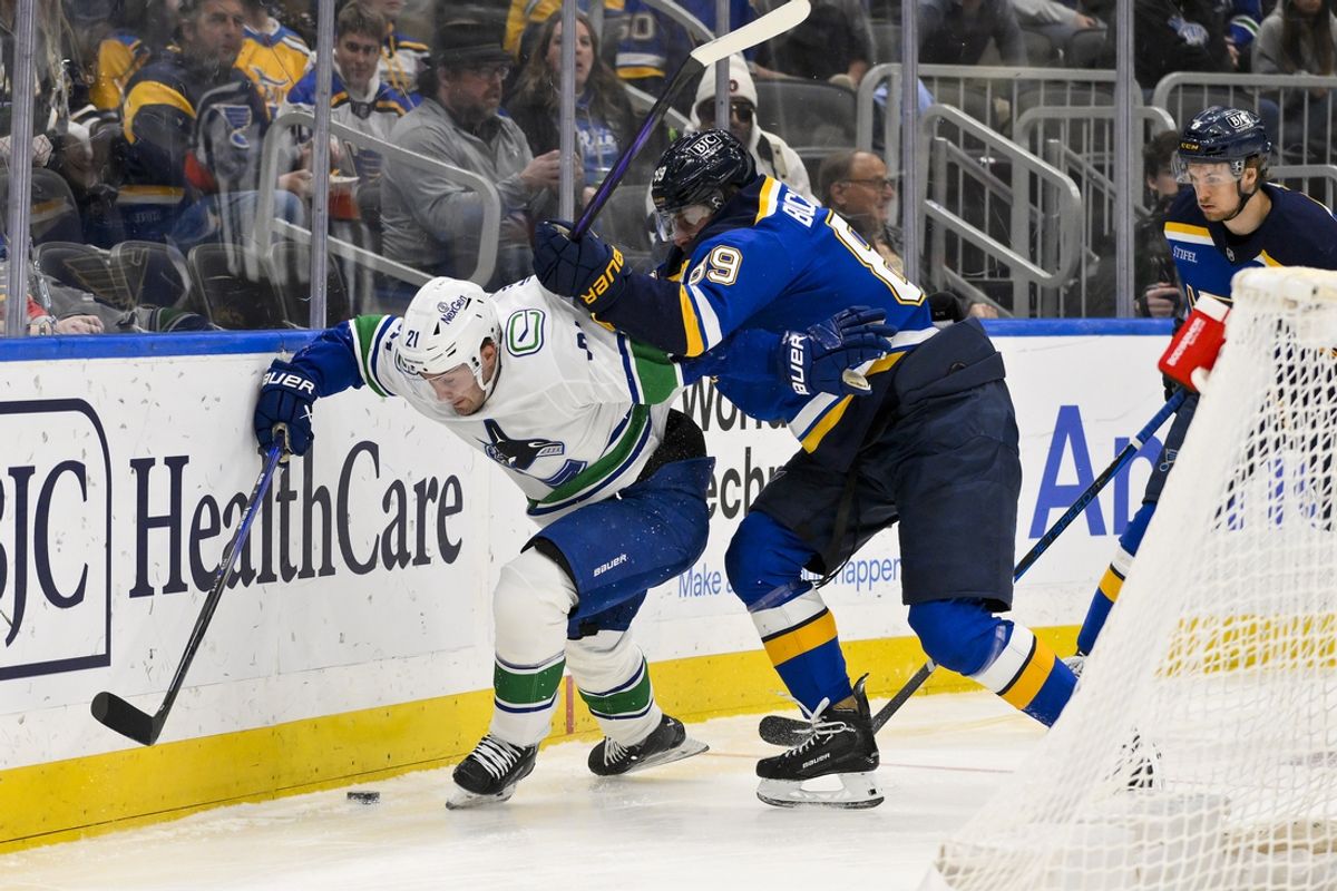 Mar 20, 2025; St. Louis, Missouri, USA;  Vancouver Canucks left wing Nils Hoglander (21) and St. Louis Blues left wing Pavel Buchnevich (89) battle for the puck during the first period at Enterprise Center. Mandatory Credit: Jeff Curry-Imagn Images