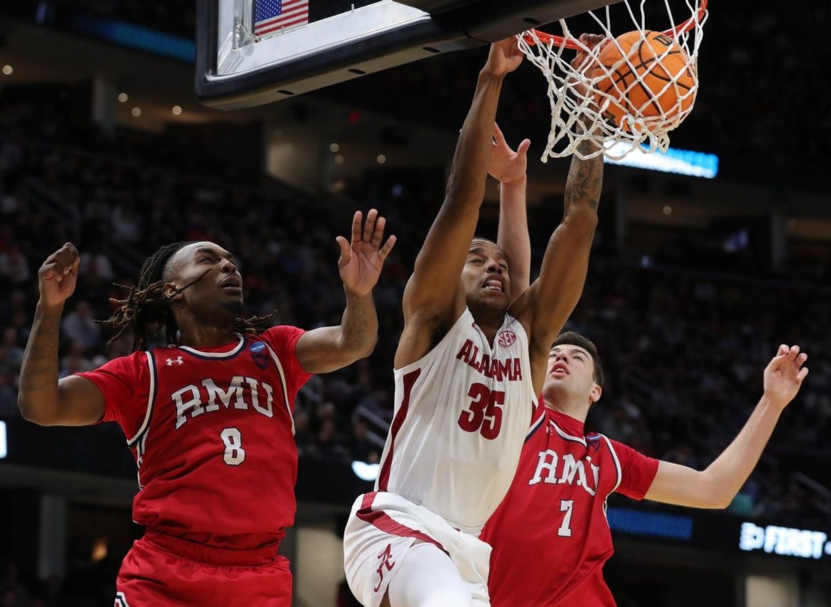 Alabama Crimson Tide forward Derrion Reid (35) throws down a dunk between Robert Morris Colonials guard Kam Woods (8) and Robert Morris Colonials forward Alvaro Folgueiras (7) during the second half of an NCAA Tournament First Round game at Rocket Arena on Friday, March 21, 2025, in Cleveland, Ohio.
