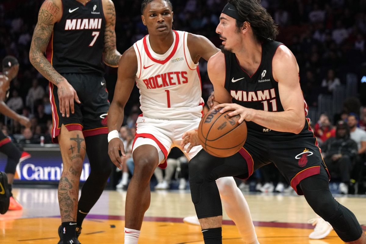 Mar 21, 2025; Miami, Florida, USA;  Miami Heat guard Jaime Jaquez Jr. (11) grabs a rebound as Houston Rockets forward Amen Thompson (1) defends at Kaseya Center. Mandatory Credit: Jim Rassol-Imagn Images