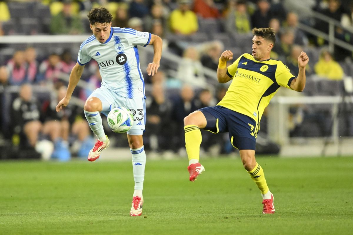 Mar 22, 2025; Nashville, Tennessee, USA;  CF Montreal midfielder Caden Clark (23) kicks the ball past Nashville SC midfielder Gaston Brugman (7) during the first half at Geodis Park. Mandatory Credit: Steve Roberts-Imagn Images