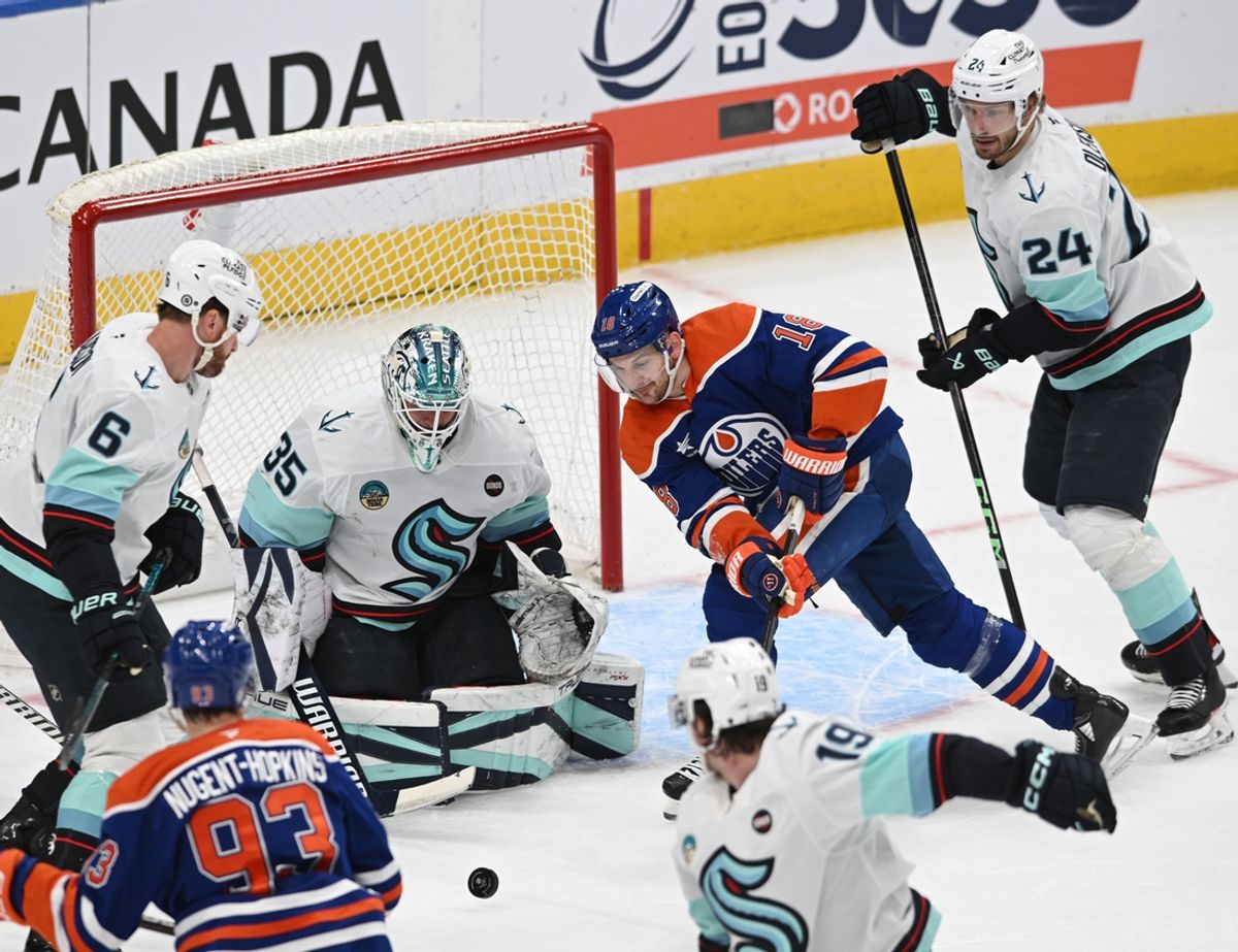 Mar 22, 2025; Edmonton, Alberta, CAN;  Seattle Kraken goalie Joey Daccord (35) looks for the puck with Edmonton Oilers left winger Zach Hyman (18) with Kraken defenceman Jamie Oleksiak (24) during the second period at Rogers Place. Mandatory Credit: Walter Tychnowicz-Imagn Images