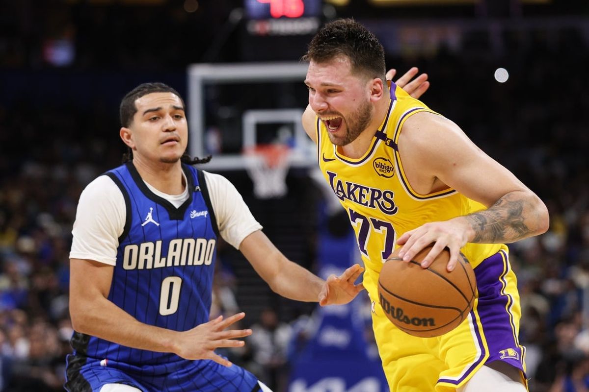 Mar 24, 2025; Orlando, Florida, USA; Los Angeles Lakers guard Luka Doncic (77) drives to the basket past Orlando Magic guard Caleb Houstan (2) in the first quarter at Kia Center. Mandatory Credit: Nathan Ray Seebeck-Imagn Images