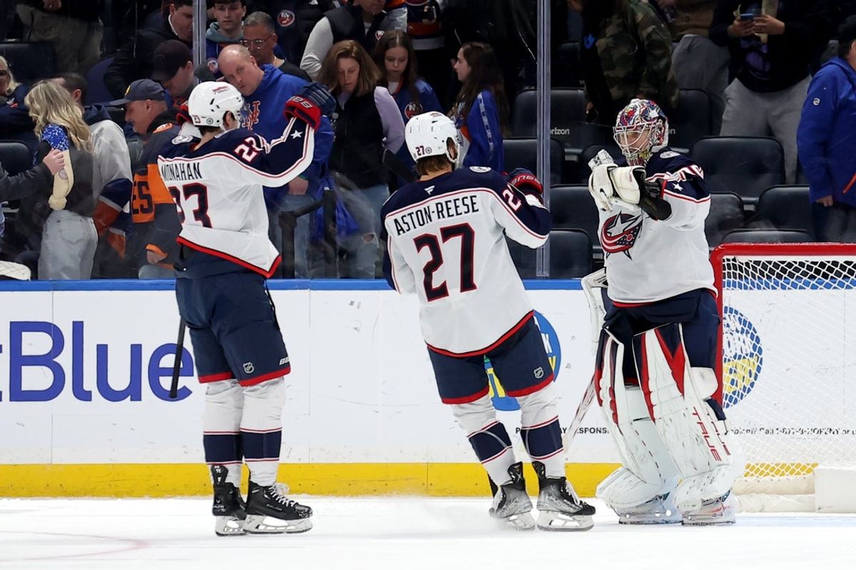 Mar 24, 2025; Elmont, New York, USA; Columbus Blue Jackets goaltender Elvis Merzlikins (90) celebrates with centers Zachary Aston-Reese (27) and Sean Monahan (23) after defeating the New York Islanders in a shootout at UBS Arena. Mandatory Credit: Brad Penner-Imagn Images