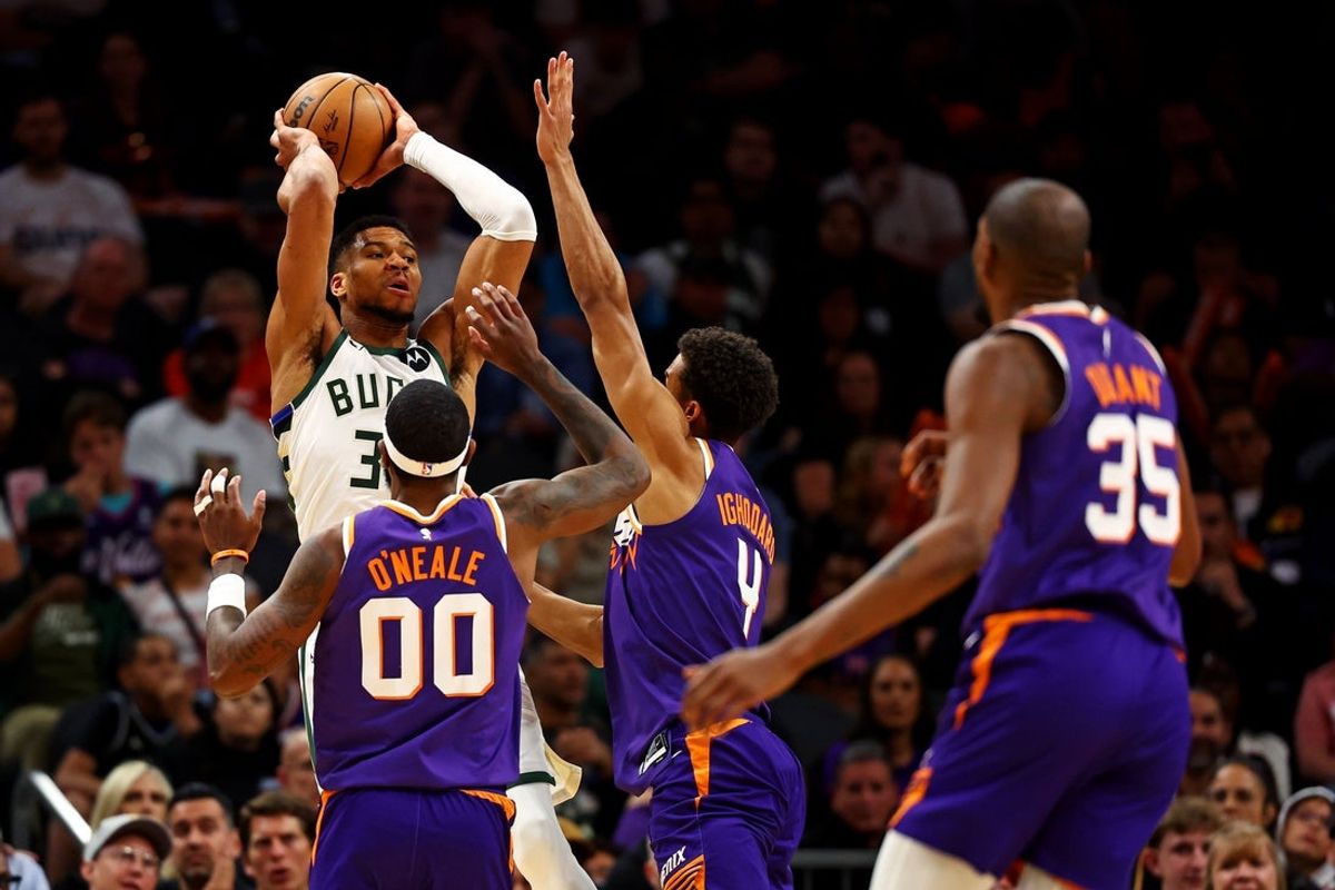Mar 24, 2025; Phoenix, Arizona, USA; Milwaukee Bucks forward Giannis Antetokounmpo (34) passes the ball against Phoenix Suns forward Royce O'Neale (00) and center Oso Ighodaro (4) during the second quarter at Footprint Center. Mandatory Credit: Mark J. Rebilas-Imagn Images