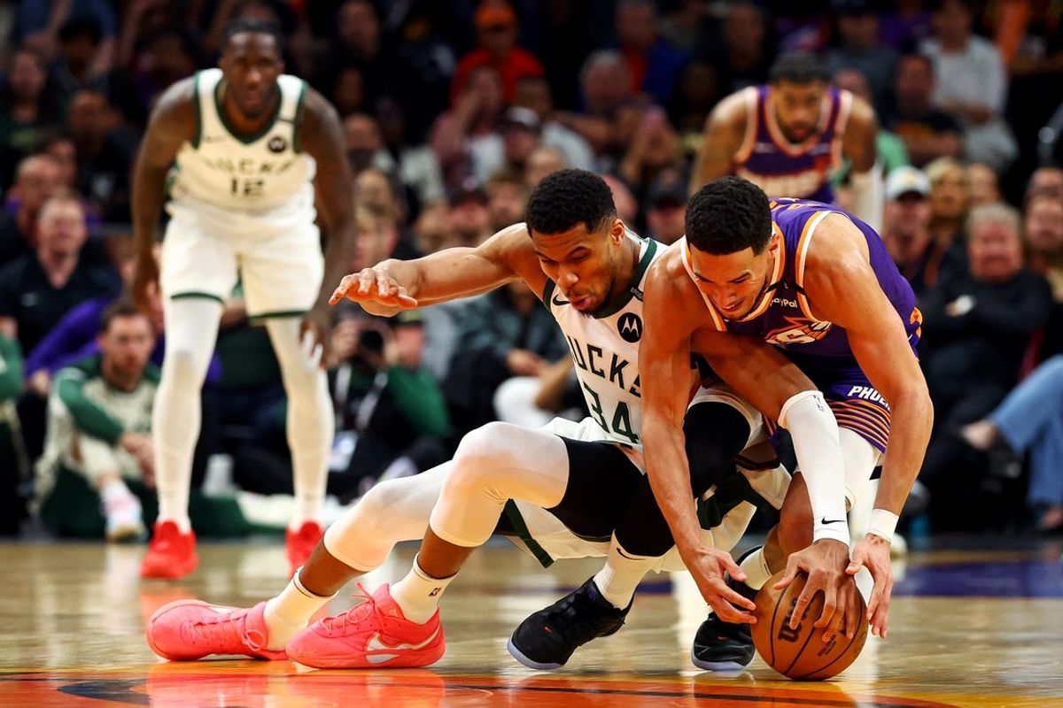 Mar 24, 2025; Phoenix, Arizona, USA; Milwaukee Bucks forward Giannis Antetokounmpo (34) and Phoenix Suns guard Devin Booker (1) go for the ball during the fourth quarter at Footprint Center. Mandatory Credit: Mark J. Rebilas-Imagn Images