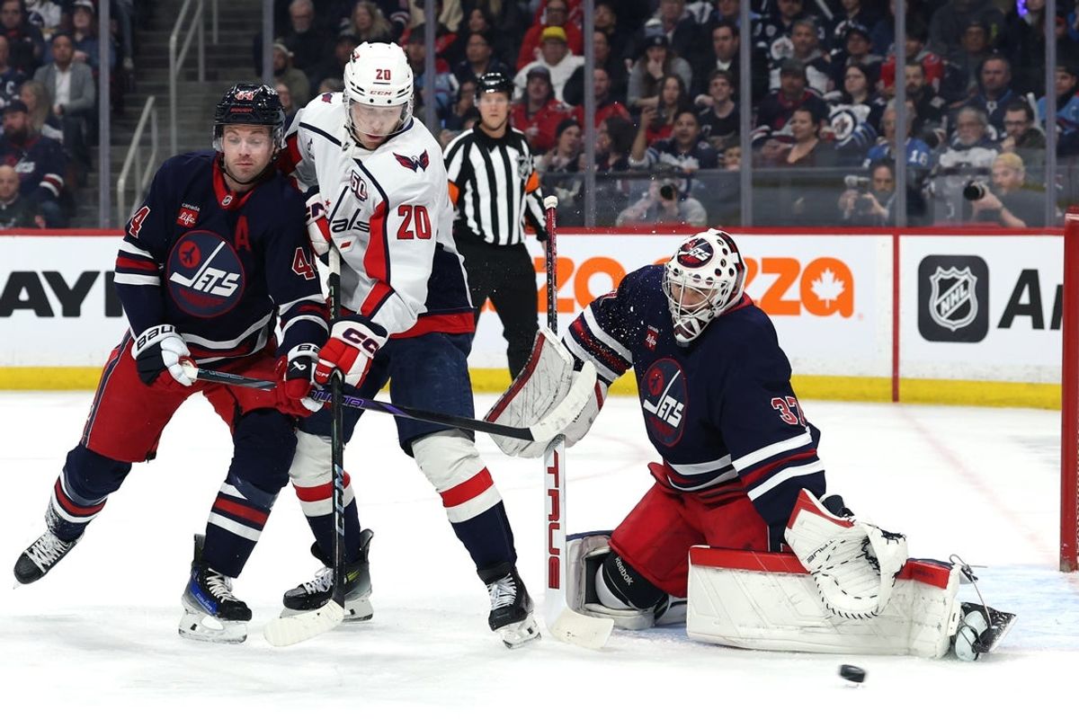 Mar 25, 2025; Winnipeg, Manitoba, CAN; Winnipeg Jets defenseman Josh Morrissey (44) and Washington Capitals center Lars Eller (20) watch the puck go wide of Winnipeg Jets goaltender Connor Hellebuyck (37) in the first period at Canada Life Centre. Mandatory Credit: James Carey Lauder-Imagn Images