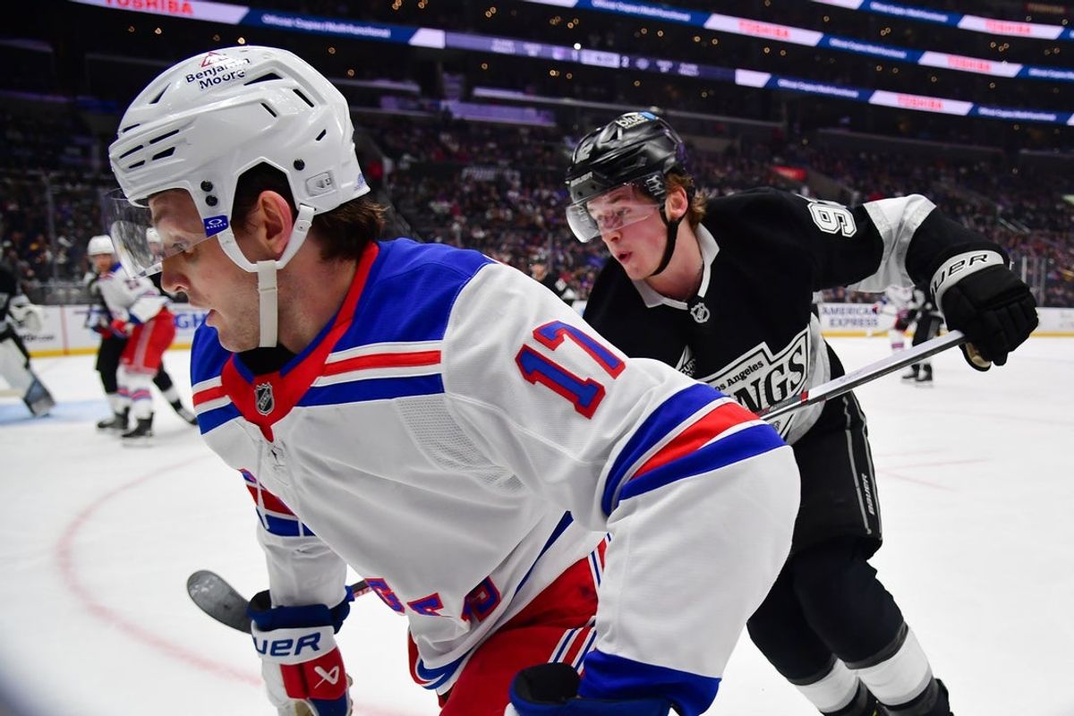 Mar 25, 2025; Los Angeles, California, USA; New York Rangers defenseman Will Borgen (17) moves the puck ahead of Los Angeles Kings defenseman Brandt Clarke (92) during the third period at Crypto.com Arena. Mandatory Credit: Gary A. Vasquez-Imagn Images