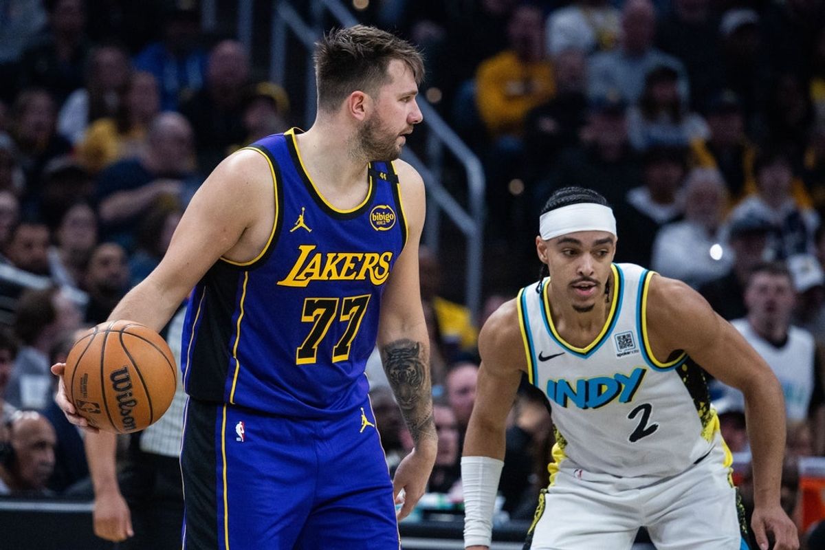 Mar 26, 2025; Indianapolis, Indiana, USA; Los Angeles Lakers guard Luka Doncic (77) dribbles the ball while  Indiana Pacers guard Andrew Nembhard (2) defends in the first half at Gainbridge Fieldhouse. Mandatory Credit: Trevor Ruszkowski-Imagn Images
