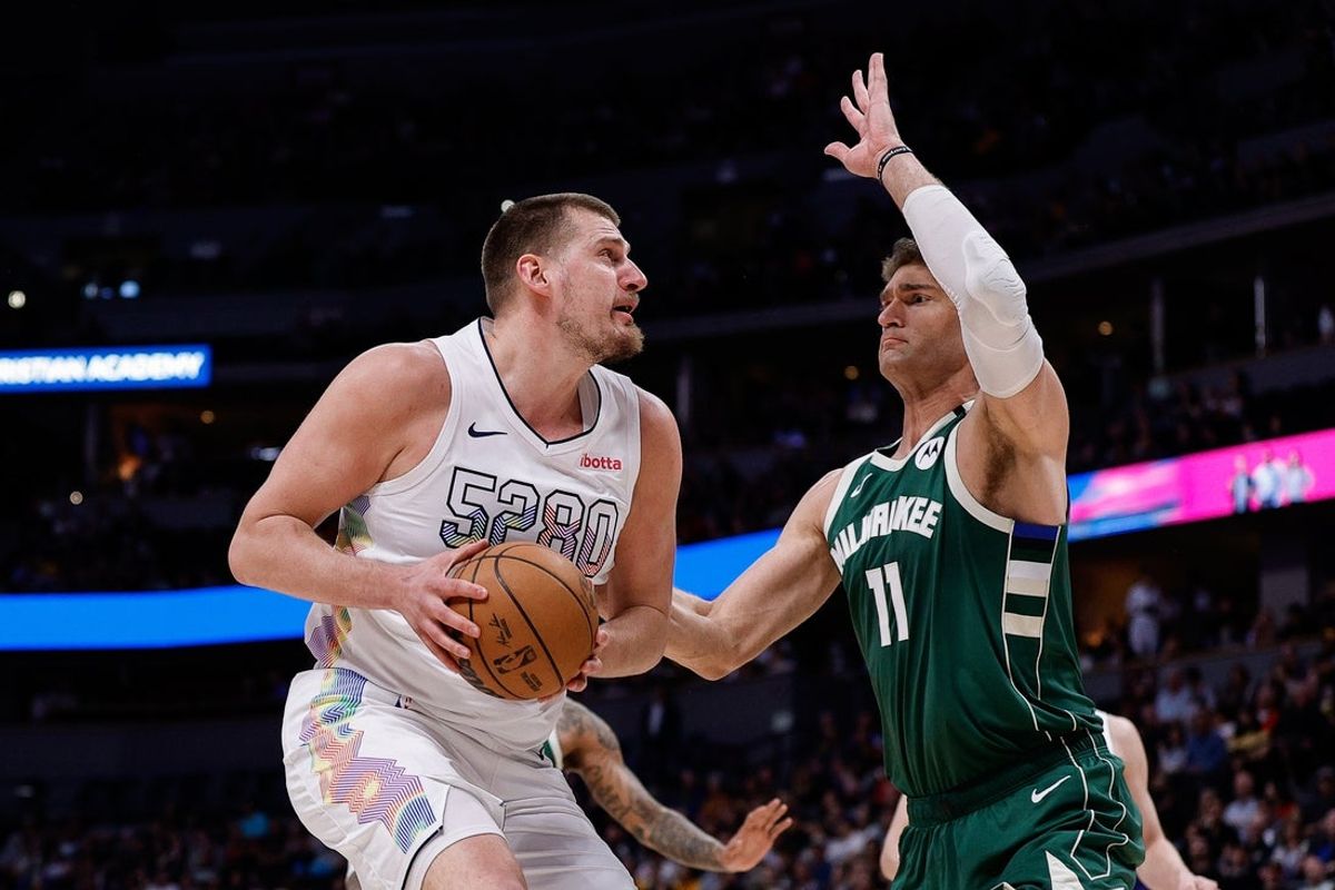 Mar 26, 2025; Denver, Colorado, USA; Denver Nuggets center Nikola Jokic (15) controls the ball as Milwaukee Bucks center Brook Lopez (11) guards in the first quarter at Ball Arena. Mandatory Credit: Isaiah J. Downing-Imagn Images