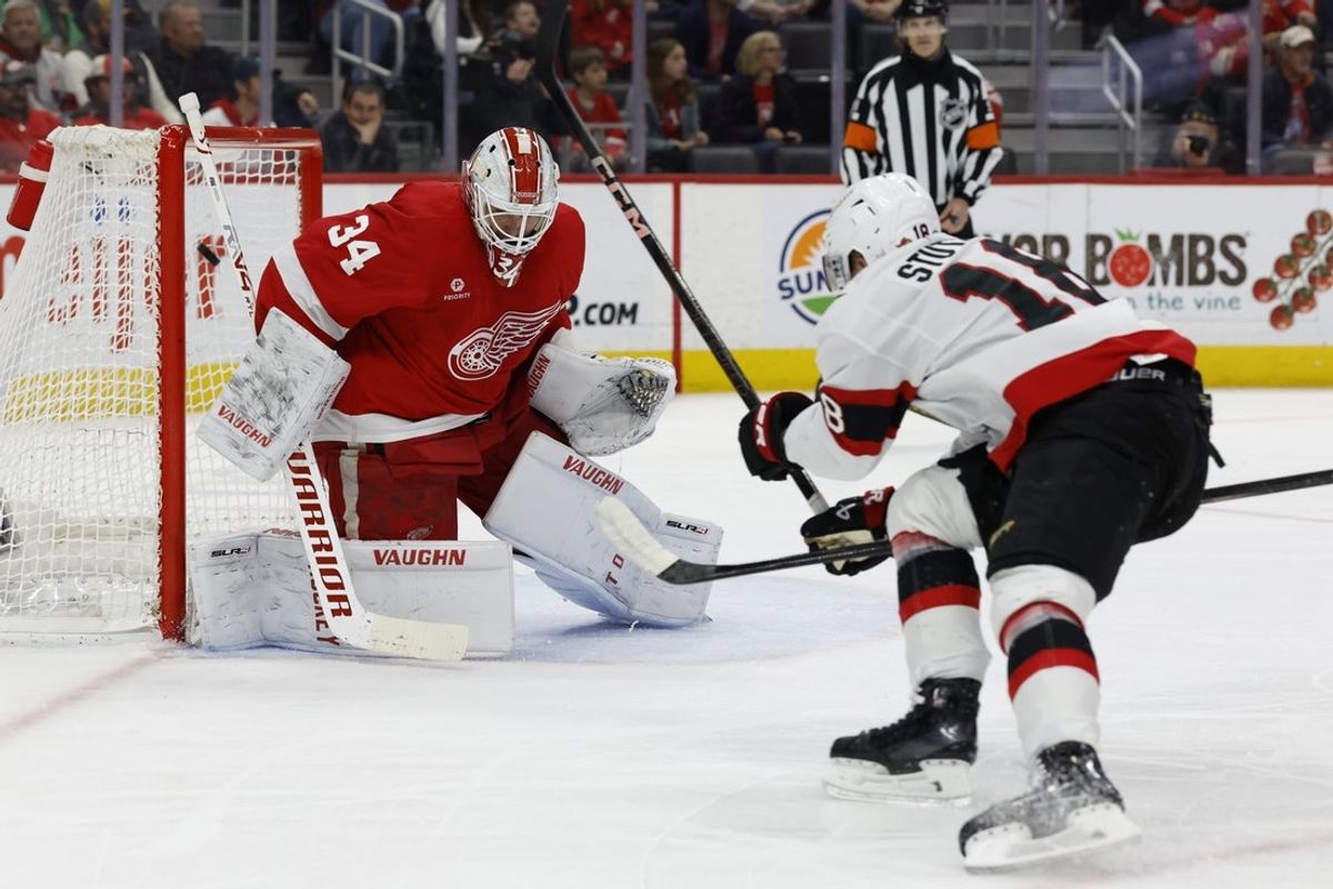 Mar 27, 2025; Detroit, Michigan, USA;  Ottawa Senators center Tim Stützle (18) scores a goal on Detroit Red Wings goaltender Alex Lyon (34) in the first period at Little Caesars Arena. Mandatory Credit: Rick Osentoski-Imagn Images