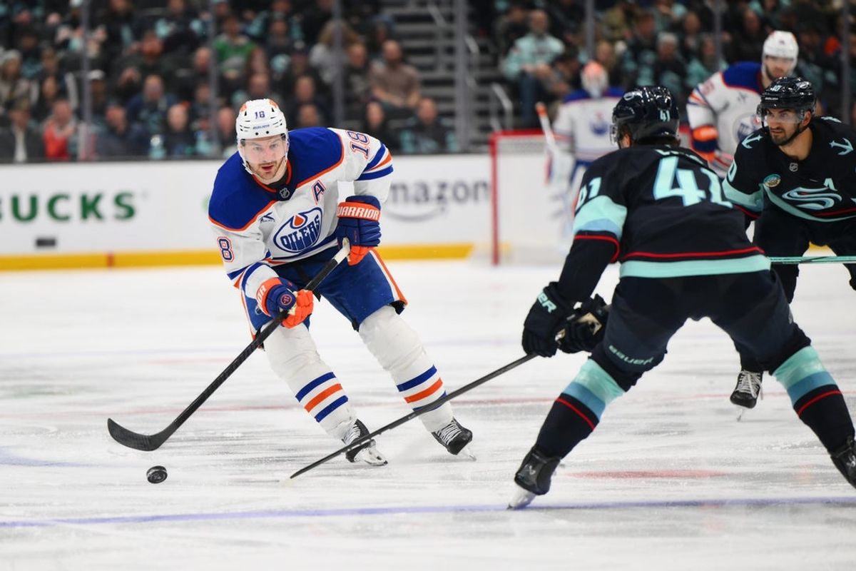 Mar 27, 2025; Seattle, Washington, USA; Edmonton Oilers left wing Zach Hyman (18) passes the puck against the Seattle Kraken during the third period at Climate Pledge Arena. Mandatory Credit: Steven Bisig-Imagn Images