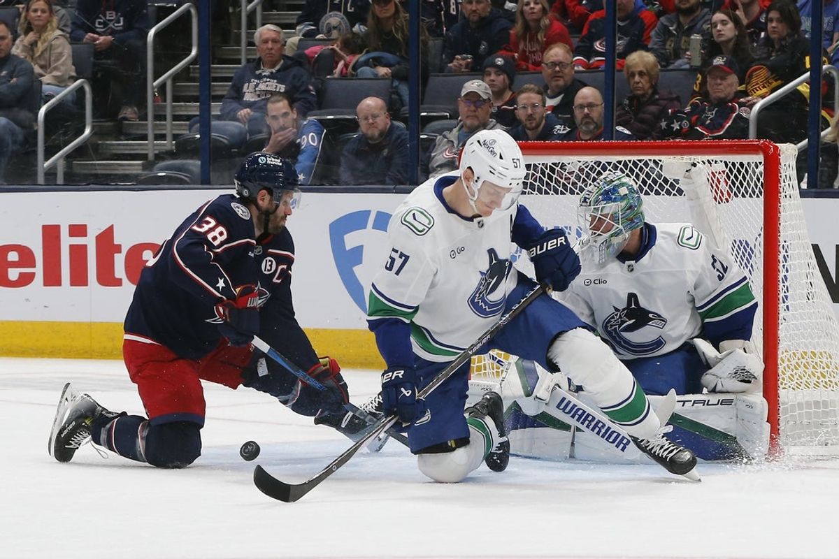 Mar 28, 2025; Columbus, Ohio, USA; Vancouver Canucks goalie Kevin Lankinen (32) makes a save as Columbus Blue Jackets center Boone Jenner (38) looks for a rebound during the first period at Nationwide Arena. Mandatory Credit: Russell LaBounty-Imagn Images