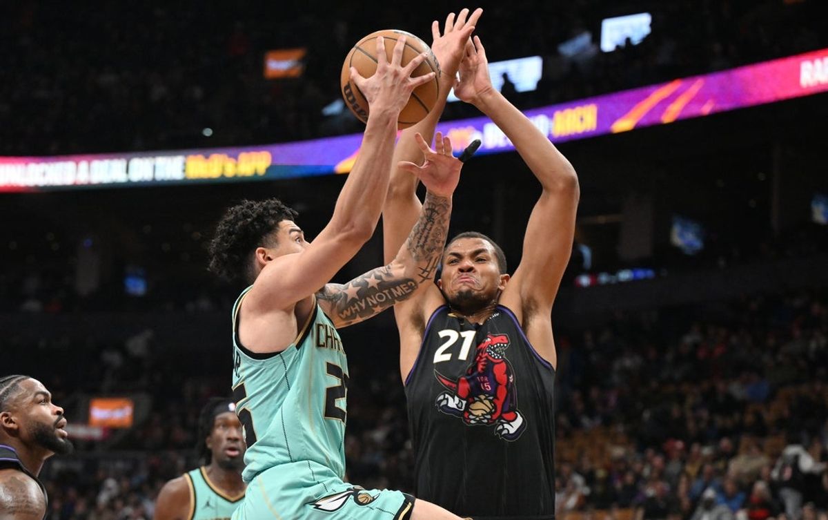 Mar 28, 2025; Toronto, Ontario, CAN;  Toronto Raptors center Orlando Robinson (21) defends his basket against Charlotte Hornets guard KJ Simpson Jr. (25) in the second half at Scotiabank Arena. Mandatory Credit: Dan Hamilton-Imagn Images
