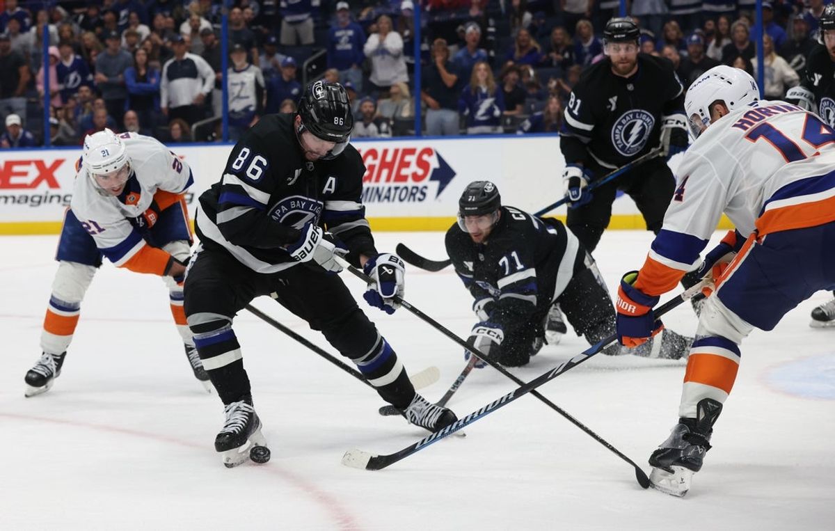 Mar 29, 2025; Tampa, Florida, USA; Tampa Bay Lightning right wing Nikita Kucherov (86) defends the puck  from New York Islanders center Kyle Palmieri (21) and New York Islanders center Bo Horvat (14) during the third period at Amalie Arena. Mandatory Credit: Kim Klement Neitzel-Imagn Images
