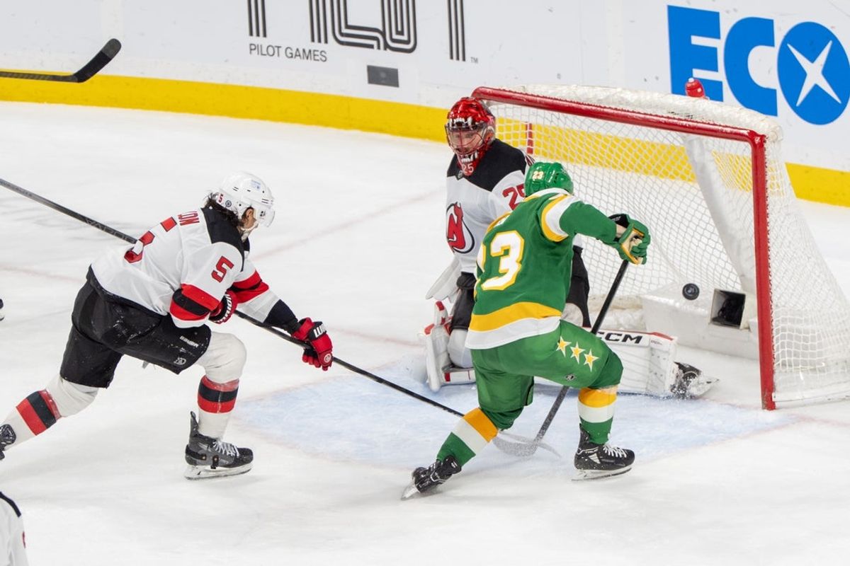 Mar 29, 2025; Saint Paul, Minnesota, USA; Minnesota Wild center Yakov Trenin (13) shoots just wide of the net as New Jersey Devils defenseman Brenden Dillon (5) is back on defense in the third period at Xcel Energy Center. Mandatory Credit: Matt Blewett-Imagn Images