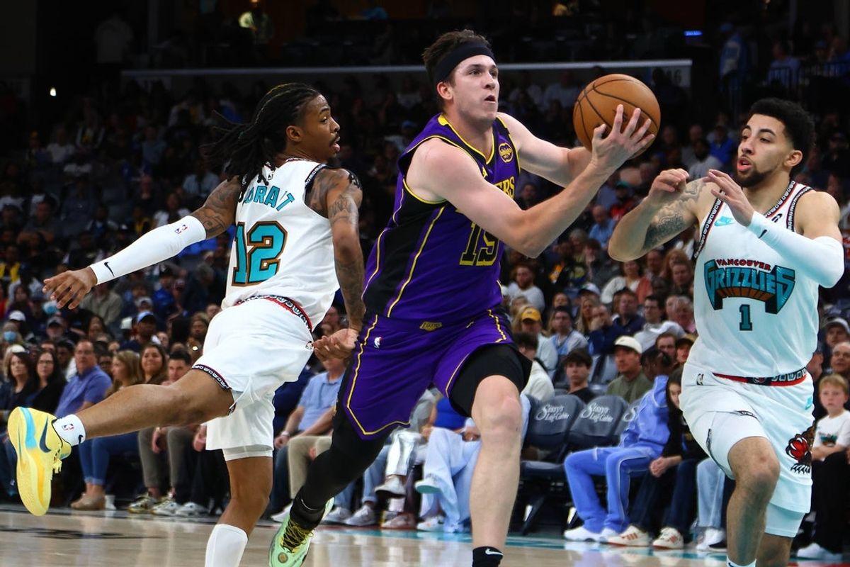 Mar 29, 2025; Memphis, Tennessee, USA; Los Angeles Lakers guard Austin Reaves (15) drives to the basket between Memphis Grizzlies guard Ja Morant (12) and Memphis Grizzlies guard Scotty Pippen Jr. (1) during the second quarter at FedExForum. Mandatory Credit: Petre Thomas-Imagn Images