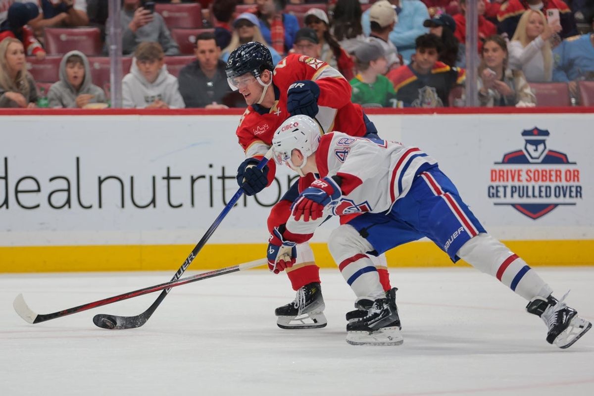 Mar 30, 2025; Sunrise, Florida, USA; Florida Panthers right wing Mackie Samoskevich (25) shoots the puck as Montreal Canadiens defenseman Lane Hutson (48) defends during the second period at Amerant Bank Arena. Mandatory Credit: Sam Navarro-Imagn Images