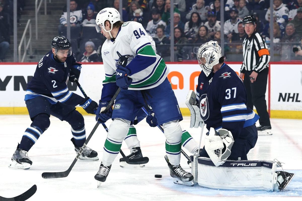 Mar 30, 2025; Winnipeg, Manitoba, CAN; Vancouver Canucks center Linus Karlsson (94) looks for a rebound in front of Winnipeg Jets goaltender Connor Hellebuyck (37) in the first period at Canada Life Centre. Mandatory Credit: James Carey Lauder-Imagn Images