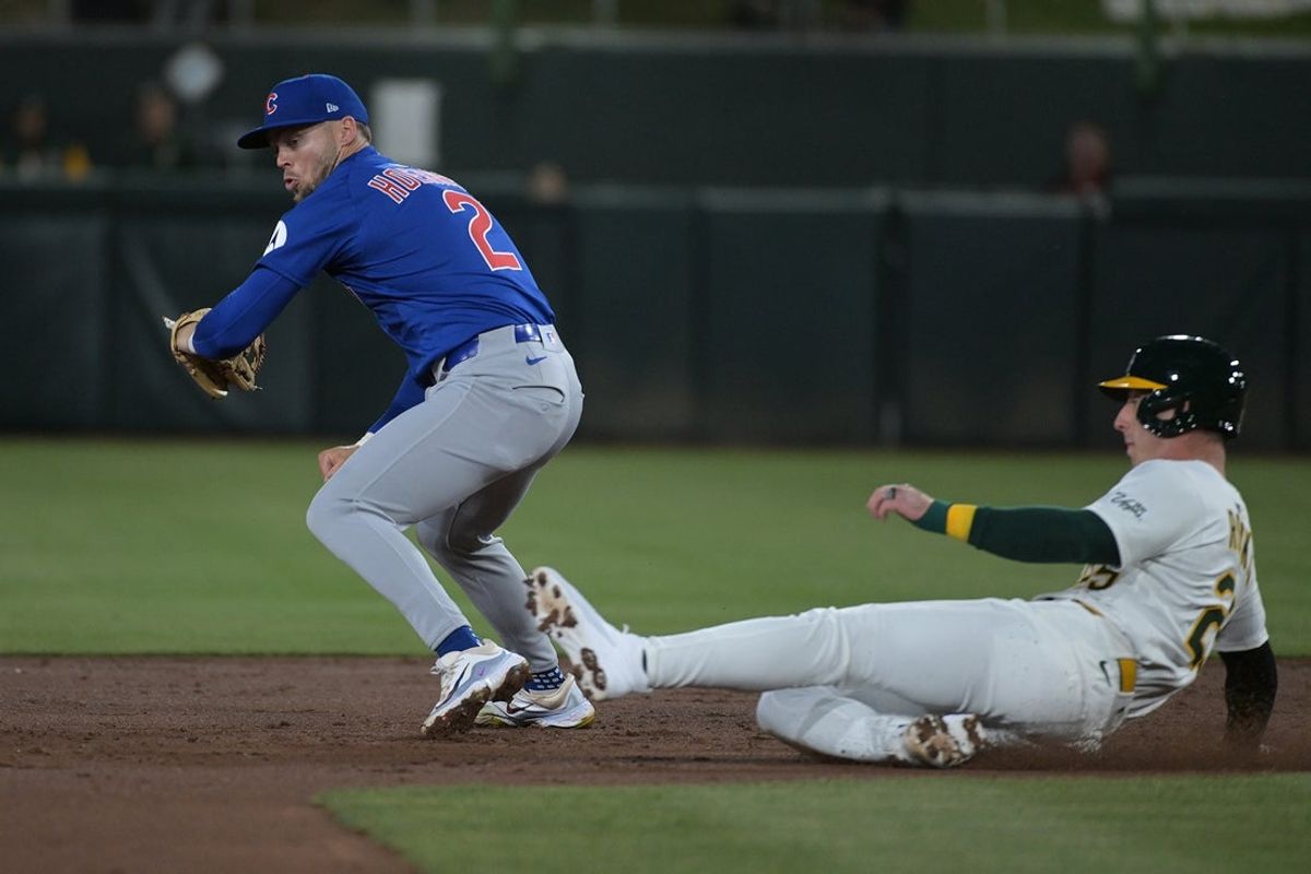 Apr 1, 2025; West Sacramento, California, USA; Chicago Cubs second base Nico Hoerner (2) attempts to tag out Athletics designated hitter Brent Rooker (25) at second base during the second inning at Sutter Health Park. Mandatory Credit: Ed Szczepanski-Imagn Images