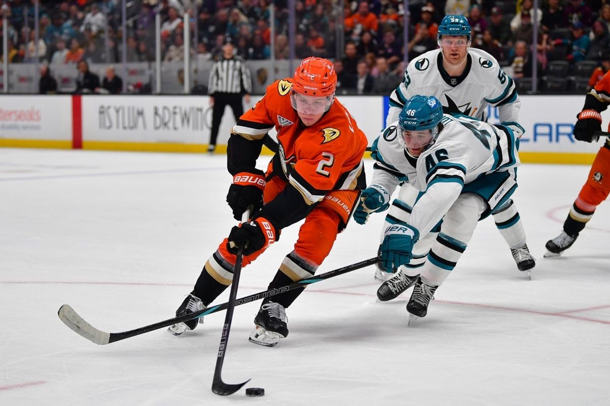 Apr 1, 2025; Anaheim, California, USA; Anaheim Ducks defenseman Jackson LaCombe (2) moves the puck against San Jose Sharks center Cam Lund (46) during the second period at Honda Center. Mandatory Credit: Gary A. Vasquez-Imagn Images