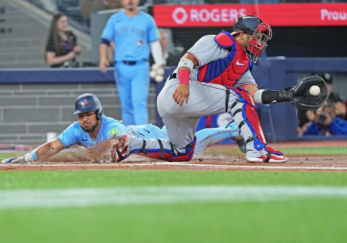 Apr 2, 2025; Toronto, Ontario, CAN; Toronto Blue Jays right fielder Anthony Santander (25) slides into home scoring a run ahead of the tag from Washington Nationals catcher Keibert Ruiz (20) during the first inning at Rogers Centre. Mandatory Credit: Nick Turchiaro-Imagn Images