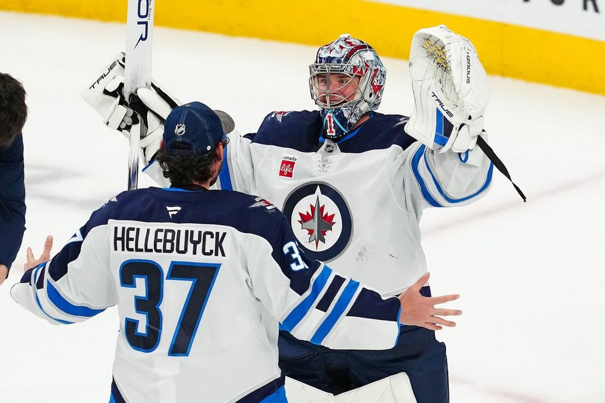 Apr 3, 2025; Las Vegas, Nevada, USA; Winnipeg Jets goaltender Eric Comrie (1) celebrates with Winnipeg Jets goaltender Connor Hellebuyck (37) after shutting out the Vegas Golden Knights 4-0 at T-Mobile Arena. Mandatory Credit: Stephen R. Sylvanie-Imagn Images