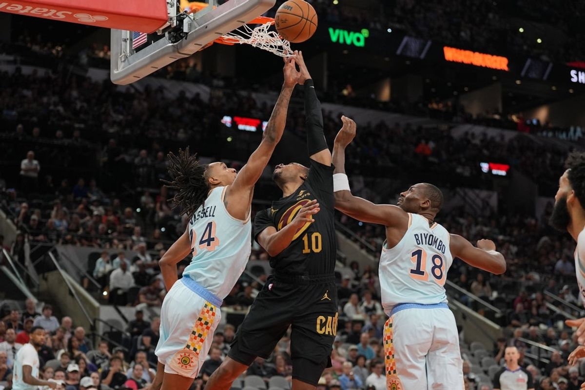 Apr 4, 2025; San Antonio, Texas, USA;  Cleveland Cavaliers guard Darius Garland (10) shoots in between San Antonio Spurs guard Devin Vassell (24) and center Bismack Biyombo (18) in the first half at Frost Bank Center. Mandatory Credit: Daniel Dunn-Imagn Images