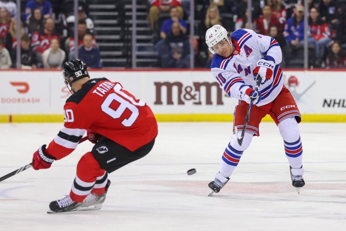 Apr 5, 2025; Newark, New Jersey, USA; New York Rangers left wing Artemi Panarin (10) shoots the puck as New Jersey Devils left wing Tomas Tatar (90) defends during the first period at Prudential Center. Mandatory Credit: Ed Mulholland-Imagn Images