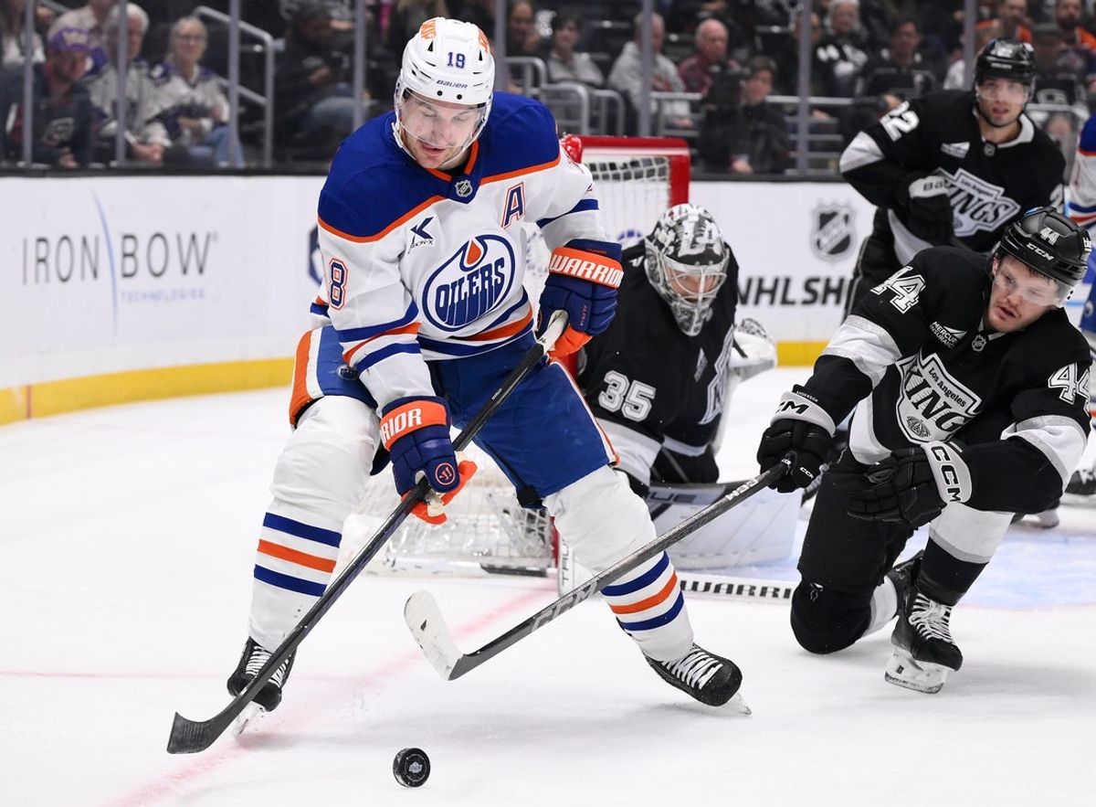Apr 5, 2025; Los Angeles, California, USA; Edmonton Oilers left wing Zach Hyman (18) tries to control the puck as Los Angeles Kings defenseman Mikey Anderson (44) moves in to defend during the first period at Crypto.com Arena. Mandatory Credit: Robert Hanashiro-Imagn Images