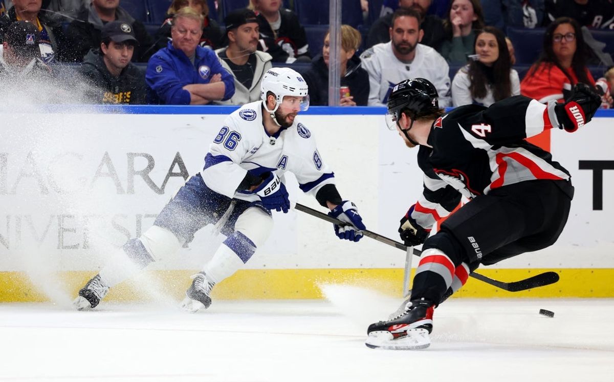 Apr 5, 2025; Buffalo, New York, USA;  Buffalo Sabres defenseman Bowen Byram (4) tries to block a pass y Tampa Bay Lightning right wing Nikita Kucherov (86) during the first period at KeyBank Center. Mandatory Credit: Timothy T. Ludwig-Imagn Images