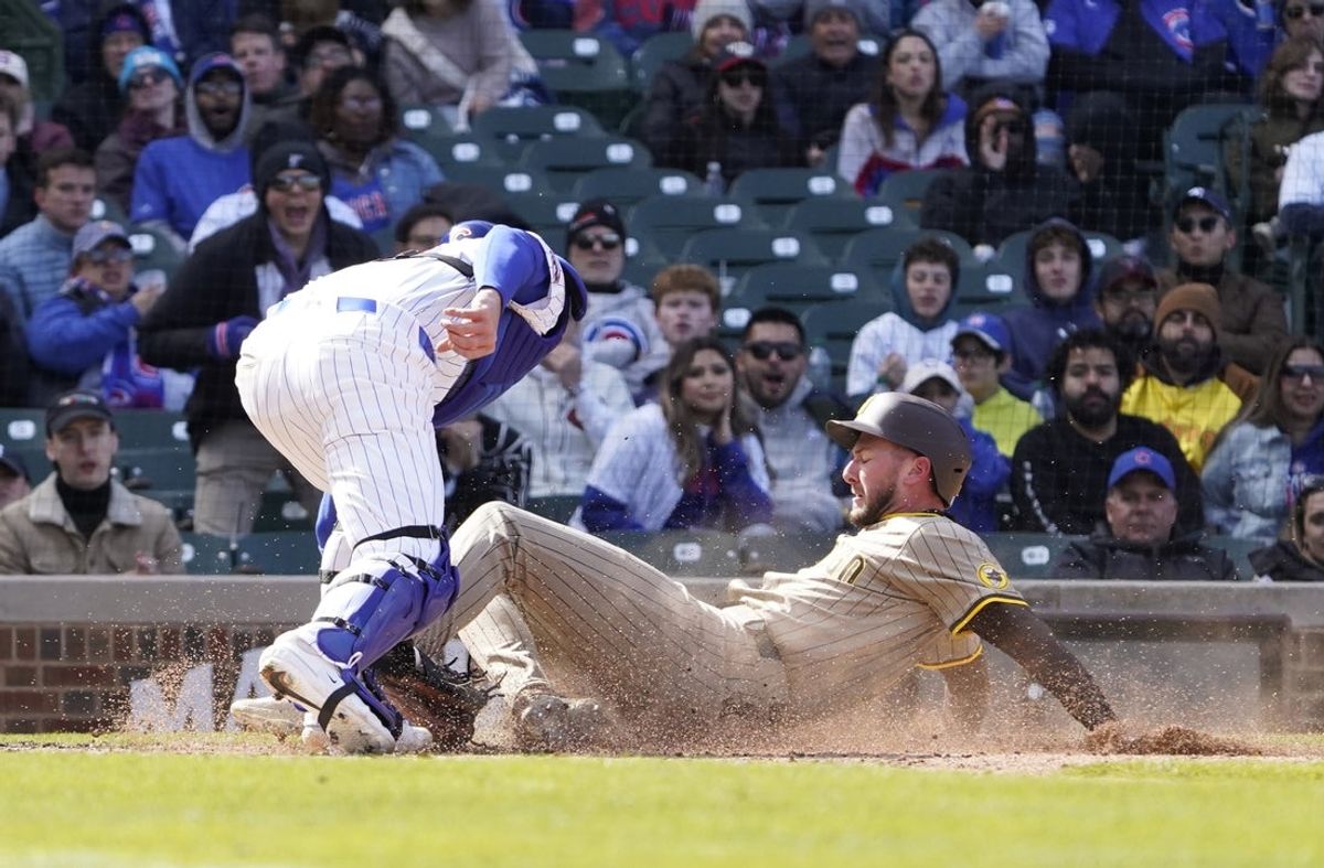 Apr 6, 2025; Chicago, Illinois, USA; Chicago Cubs catcher Carson Kelly (15) tags out San Diego Padres outfielder Jackson Merrill (3) at home plate during the sixth inning at Wrigley Field. Mandatory Credit: David Banks-Imagn Images