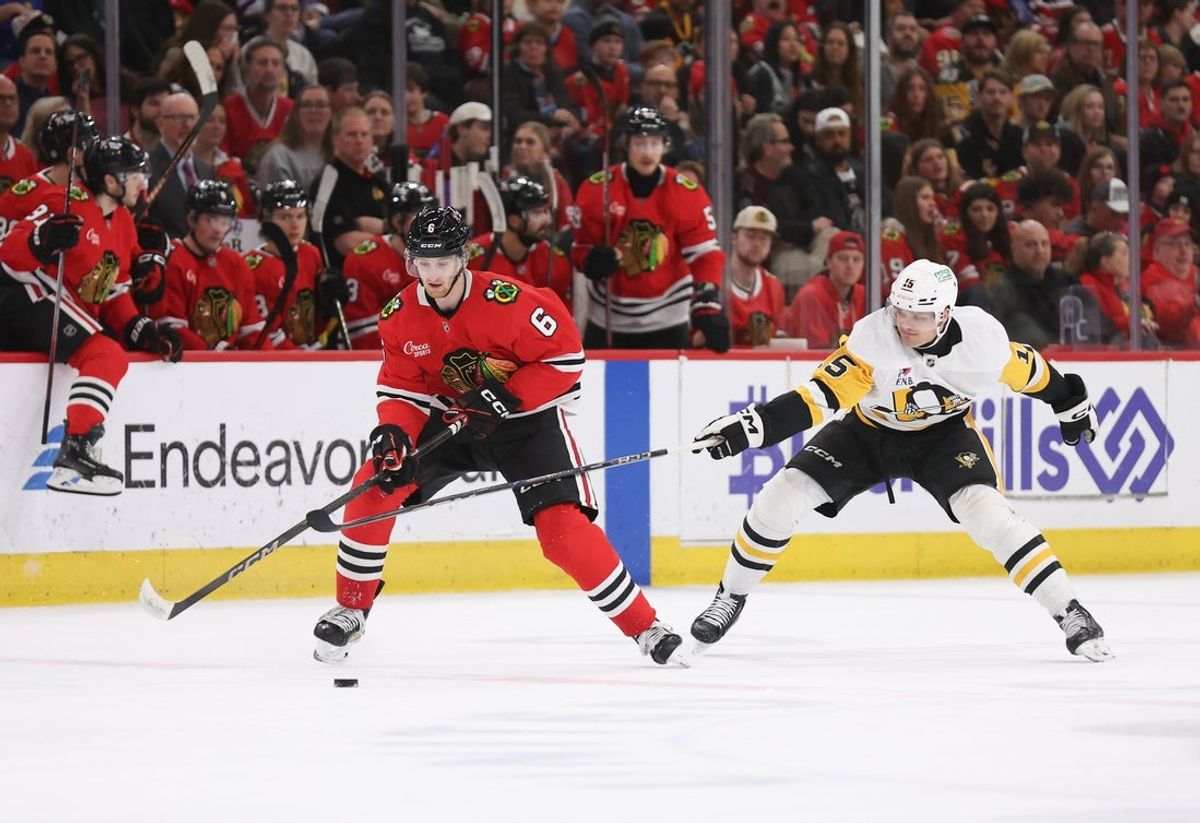 Apr 6, 2025; Chicago, Illinois, USA; Chicago Blackhawks defenseman Sam Rinzel (6) and Pittsburgh Penguins left wing Joona Koppanen (15) battle for control of the puck during the second period at United Center. Mandatory Credit: Talia Sprague-Imagn Images
